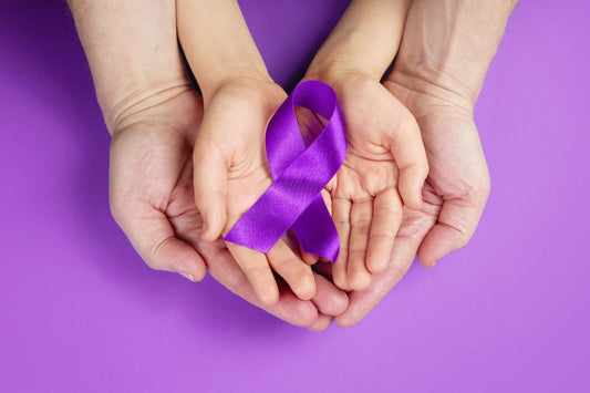 Hands holding purple ribbon to support and spread awareness for Crohn's Disease.