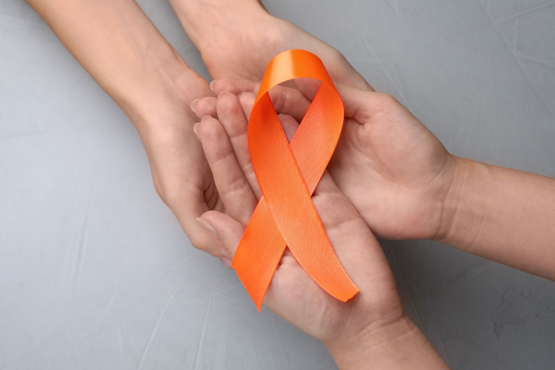 Two hands holding orange ribbon for limb loss awareness purpose.